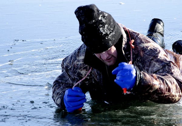 A Cass County Sheriff's Deputy uses ice picks to pull himself out of a hole in the ice as part of a recent ice rescue training exercise for first resp