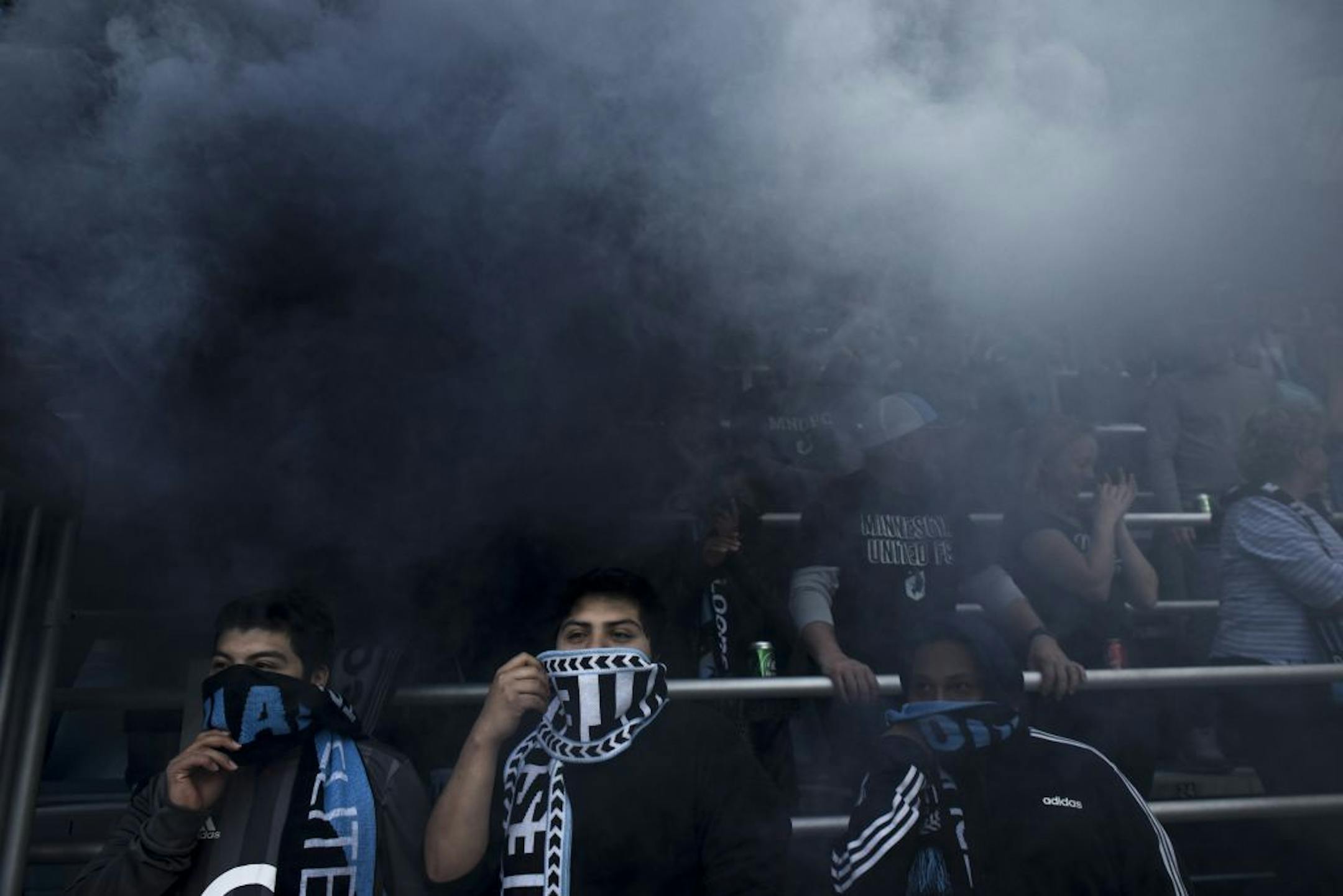 Three young Minnesota United fans covered their faces from smoke before Saturday's game against the Seattle Sounders.