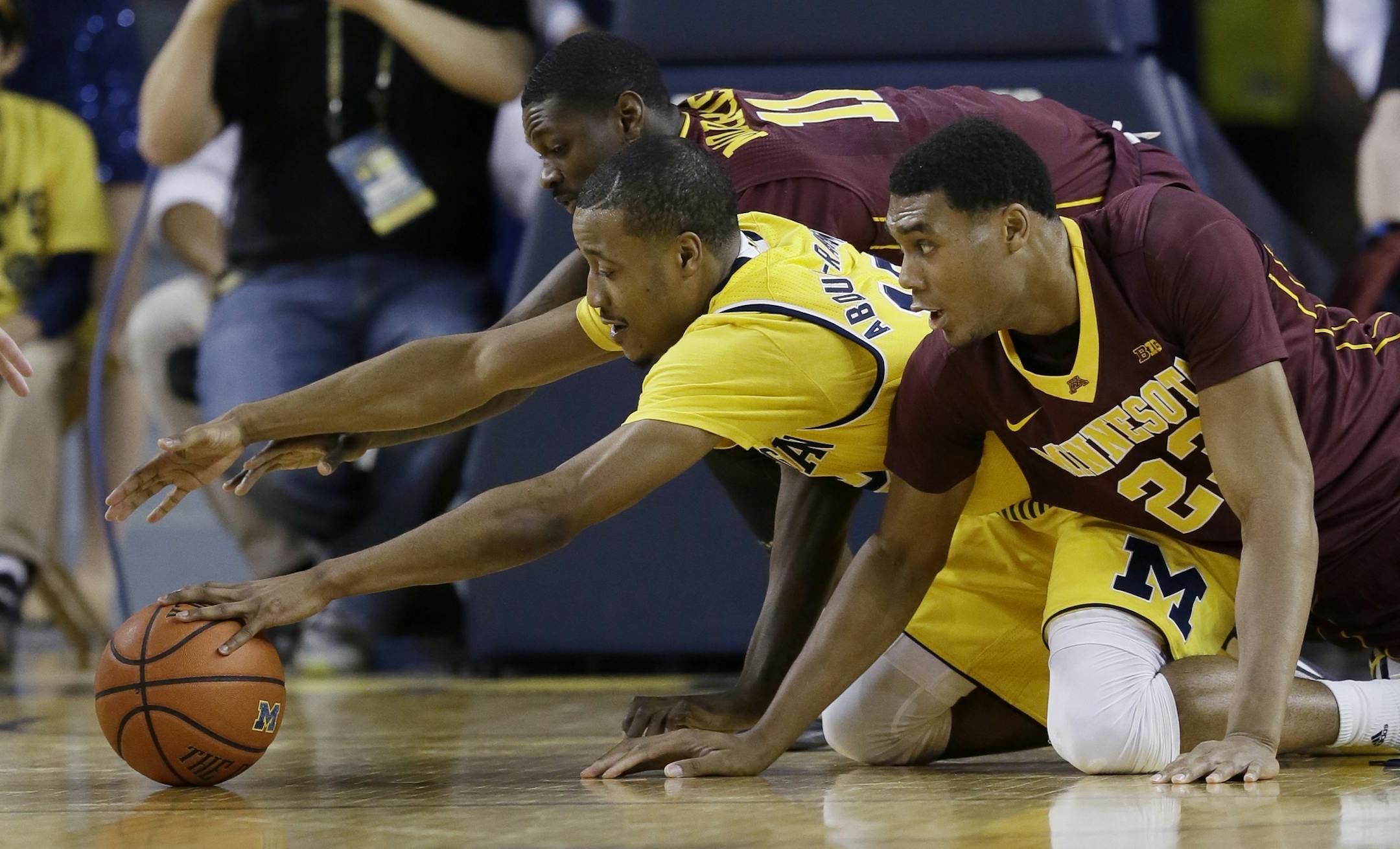 Michigan guard Muhammad-Ali Abdur-Rahkman (12), Minnesota guard Carlos Morris (11) and Minnesota forward Charles Buggs (23) fight for the loose ball during the first half of an NCAA college basketball game, Wednesday, Jan. 20, 2016 in Ann Arbor, Mich. (AP Photo/Carlos Osorio)
