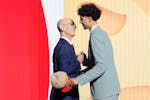 French basketball player Zaccharie Risacher, right, greets NBA Commissioner Adam Silver after being selected as the first overall pick by the Atlanta 