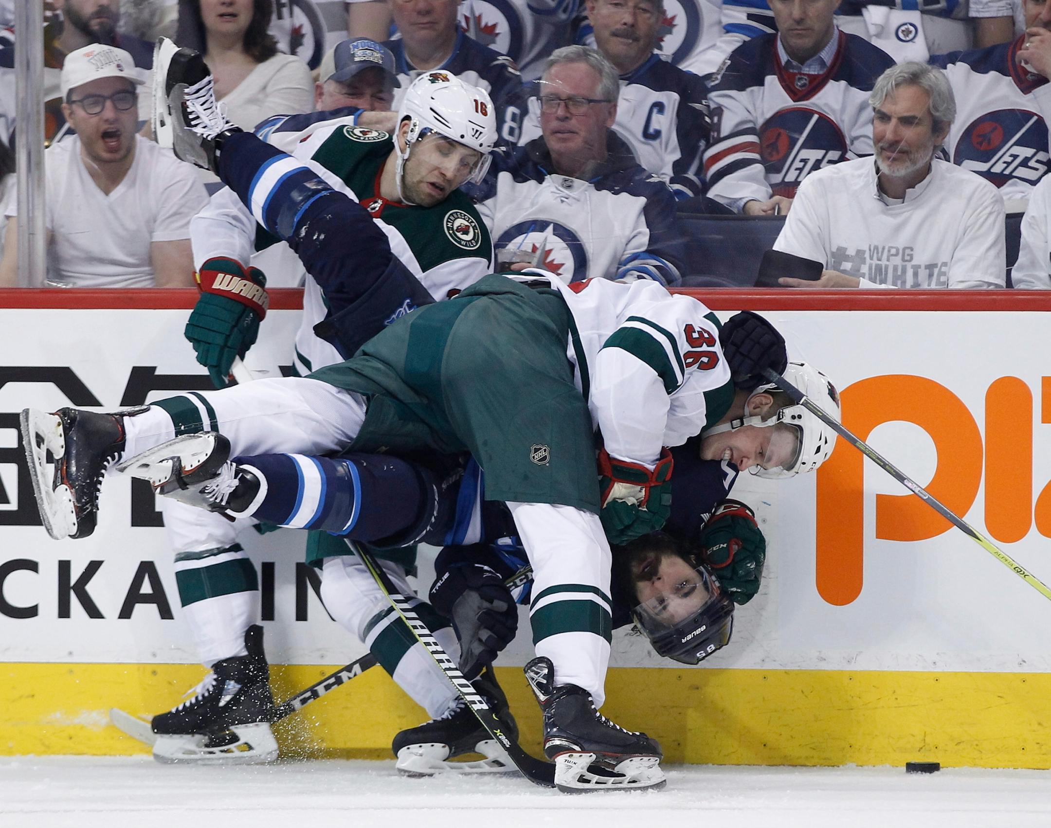 Winnipeg Jets' Mathieu Perreault (85) gets checked by Minnesota Wild's Nick Seeler (36) and Jason Zucker (16) during the second period of Game 1 in an NHL hockey first-round playoff series Wednesday, April 11, 2018, in Winnipeg, Manitoba.
