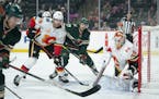 Wild left wing Marcus Foligno (17) watched for a centering pass in front of Calgary goaltender Cam Talbot while defended by Flames defenseman Noah Han