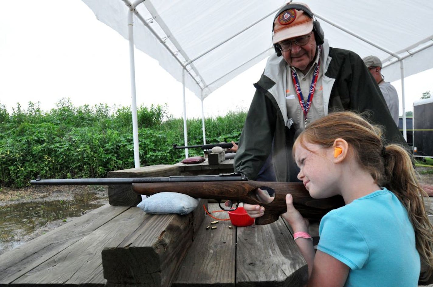 Coached by Dakota County Gun Club volunteer Mike Larson of Bloomington, Elise Nelson, 8, of Eagan, peered through the sight of a .22 caliber rifle, on her first day at the club's youth shoot in Rosemount.
Photo by Liz Rolfsmeier