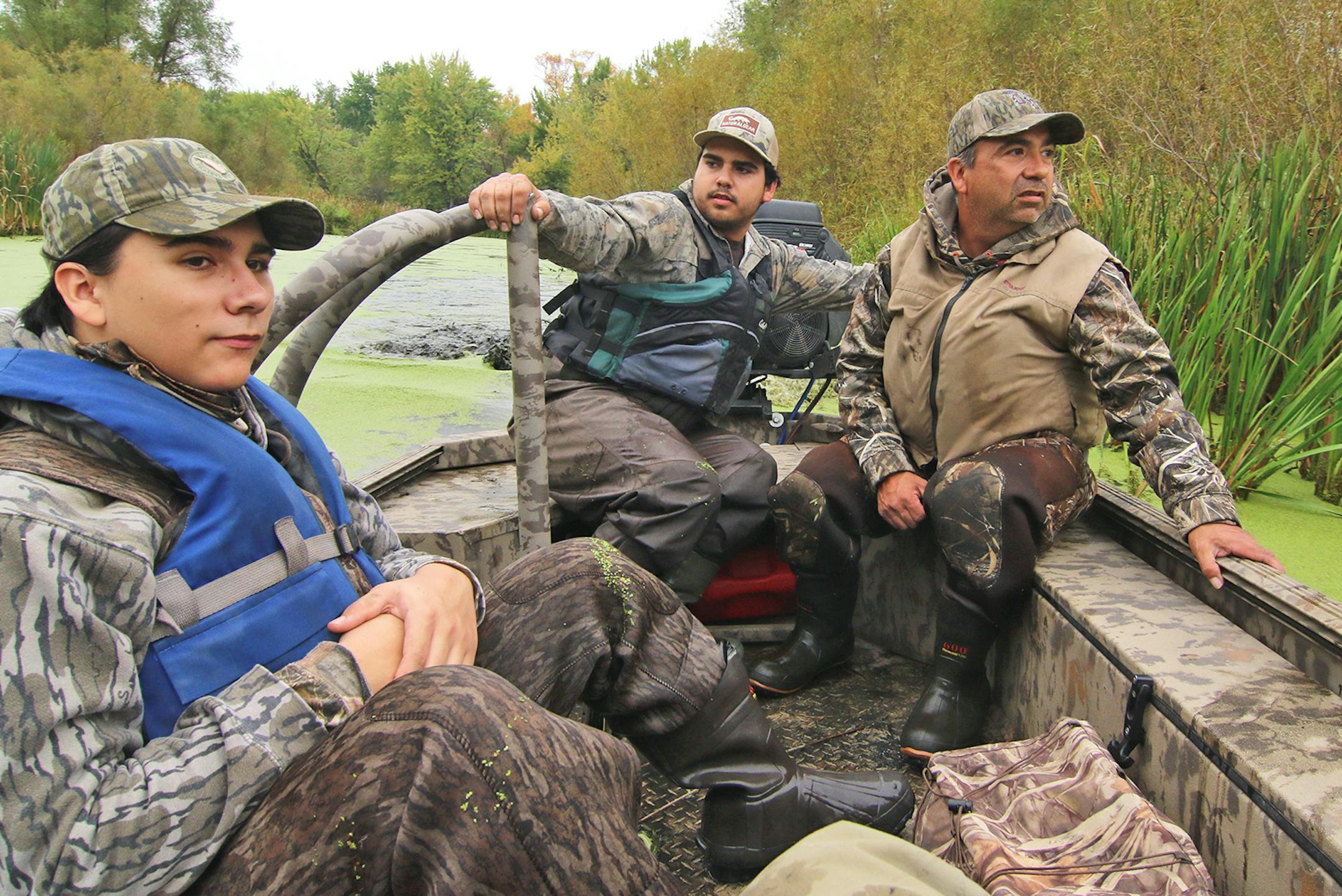 Trevor Montez, center, steered his mud boat through a backwater on the Mississippi River on his family's return from the state duck season opener north of Hastings. His father, Troy, right, and one of his three brothers, Tanner, rode along.