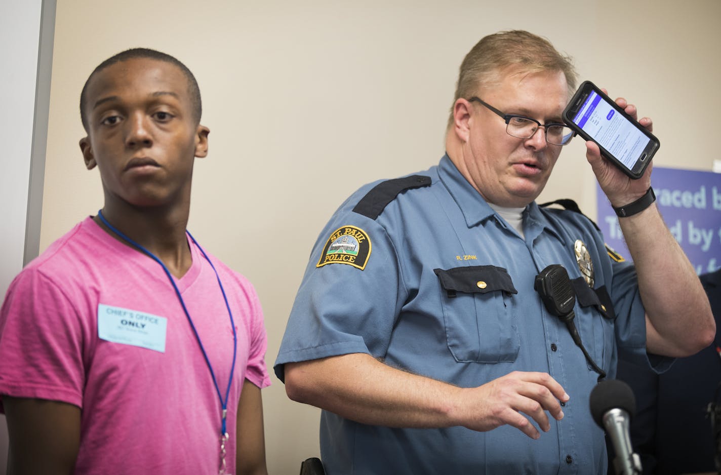 Officer Rob Zink, right, demonstrated how the Vitals information shows up on an officer's phone, accompanied by Devonte Ray-Burns, 14, of St. Paul, who has autism and uses Vitals.