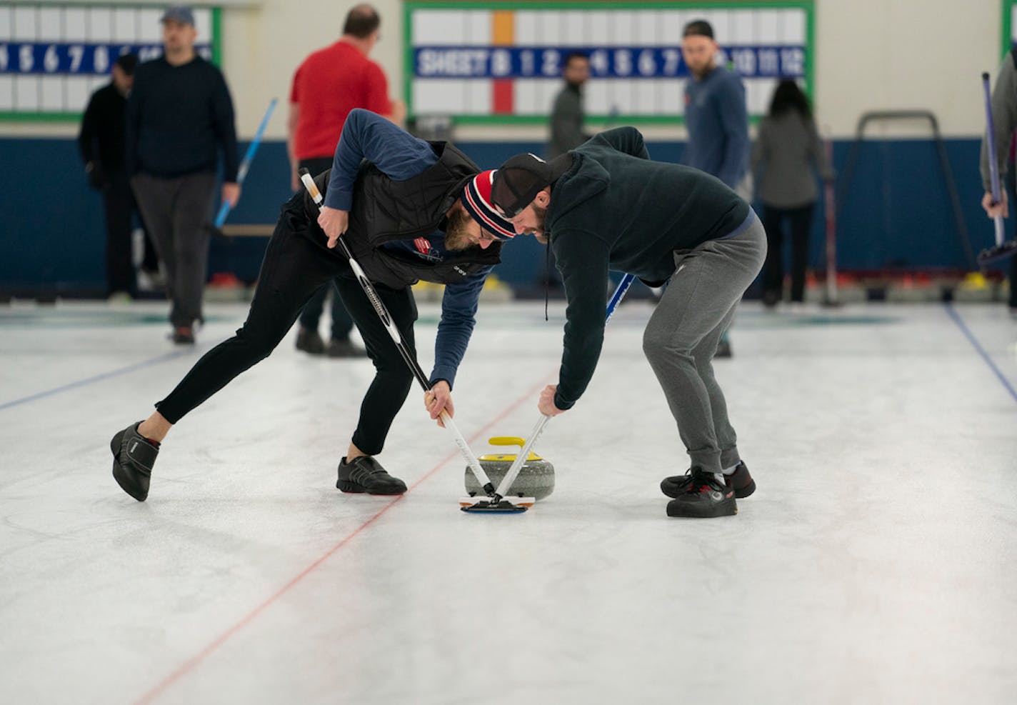 Brad Schwantke and Derek Doty swept in front of the stone during their curling league at the Four Seasons Curling Club in Blaine.