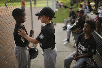 Khy Paradis, 9, center, offered support to Imraan Arale, 9, after his at bat against Kenwood-Bryn Mawr last month at Bryant Square Park. Ashraf Mohame