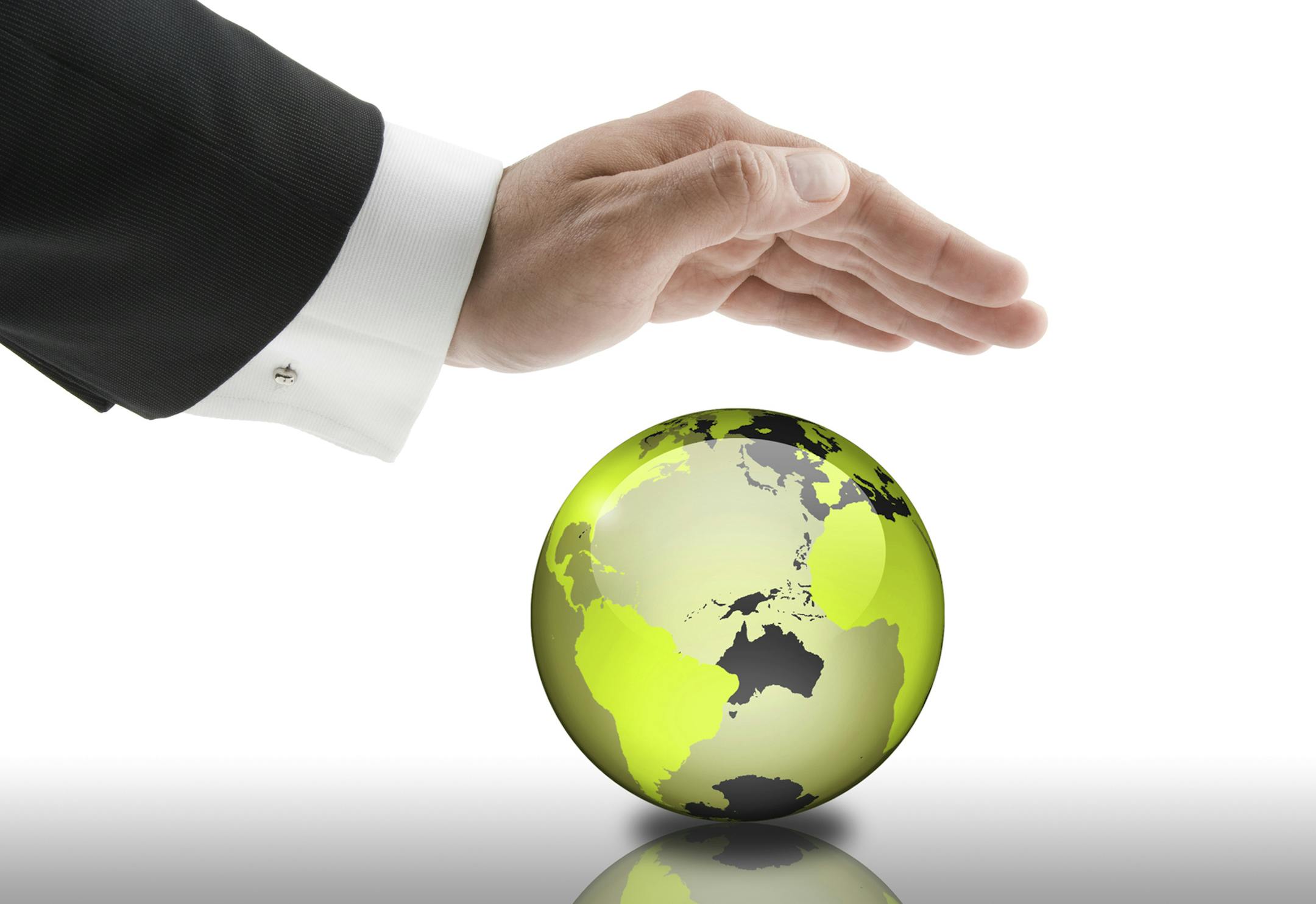 Businessman holding his hand over a green globe. Can be used for corporate social responsibility, environmental protection and nature conservation concepts.
