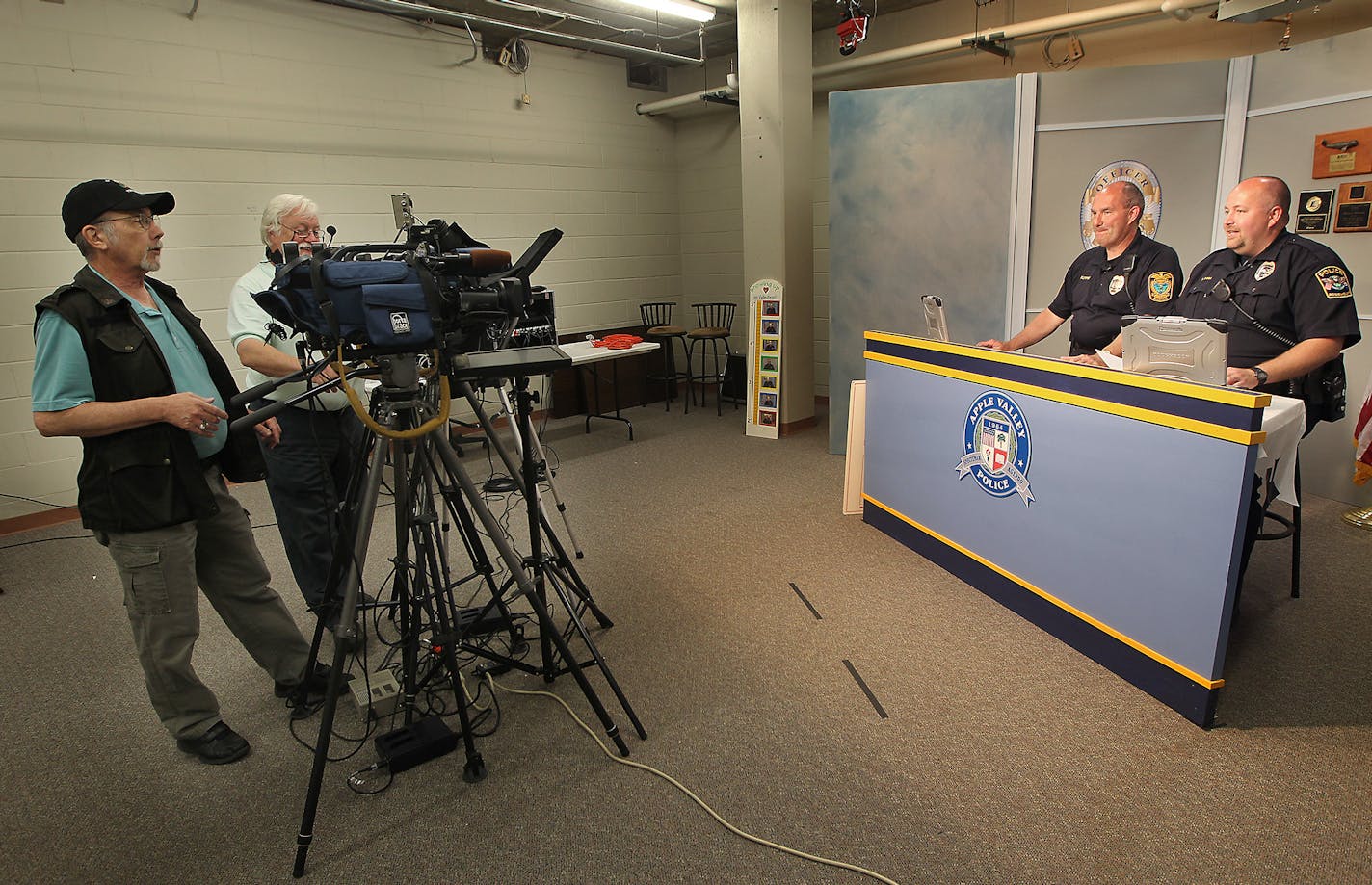 Mark Moore, cable coordinator, left, and Terry Devine, Center, taped a police show with Farmington Police officer Steve Kuyper, left, and Rosemount Police officer Chad Rosa, Wednesday, July 22, 2015 in Apple Valley, MN. Farmington Police are joining Apple Valley and Rosemount in producing a local television show about policing and public safety issues.