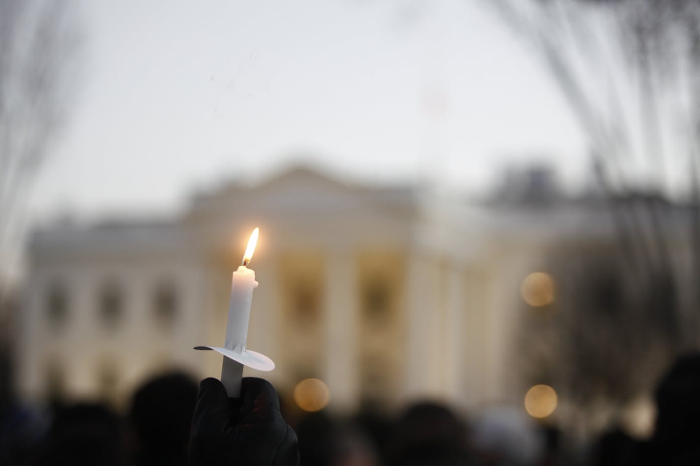 Gun control demonstrators hold a candlelight vigil, in reaction to a school shooting in Connecticut, on Pennsylvania Avenue in front of the White House in Washington, Dec. 14, 2012.