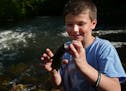 George Heinen,8, showed a catfish he and his friends cut up earlier for bait. He enjoys coming to his favorite fishing spot.] A secluded fishing hole 