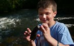 George Heinen,8, showed a catfish he and his friends cut up earlier for bait. He enjoys coming to his favorite fishing spot.] A secluded fishing hole 