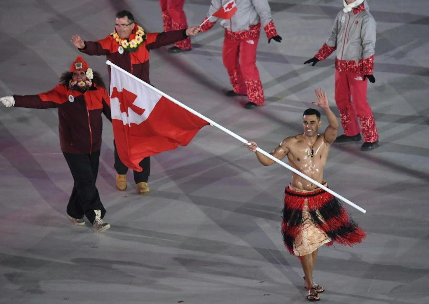 Pita Taufatofua carries the flag of Tonga during the opening ceremony of the 2018 Winter Olympics in Pyeongchang, South Korea, Friday, Feb. 9, 2018. He'll compete in cross-country skiing.