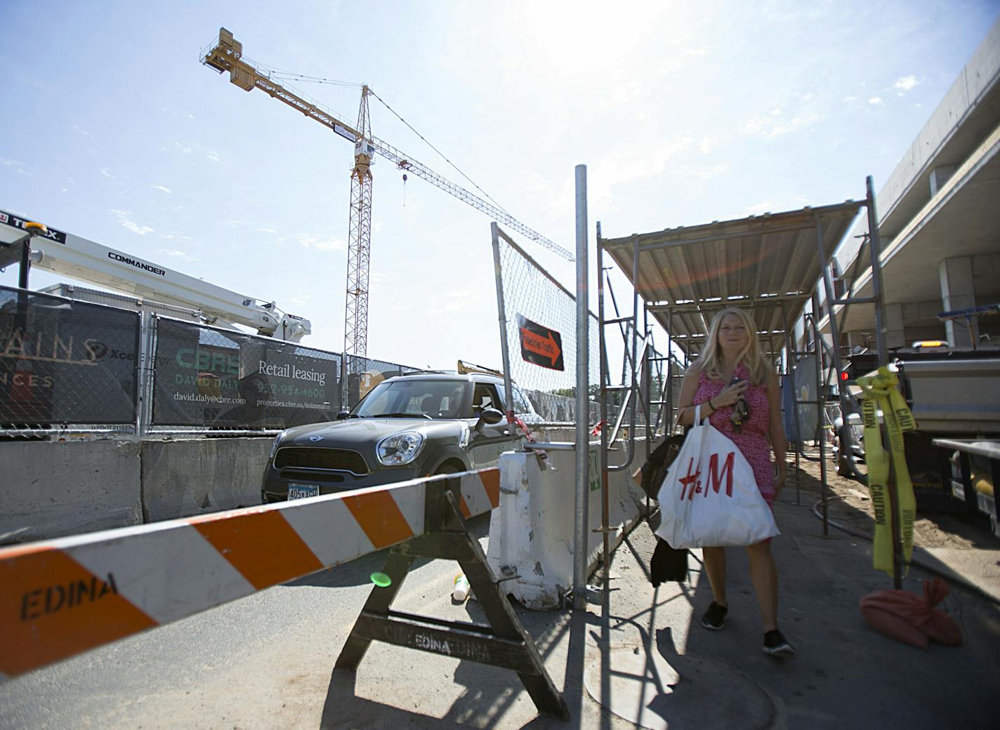 Susan Yost walked through a scaffolded pedestrian walkaway toward the shops at 50th and France. Construction of the Nolan Mains apartments and a nearby parking ramp has hurt businesses in the area.