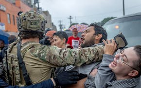 People confront law enforcement as they try to remove someone they detained outside Los Cuatro Milpas restaurant amid protest over a federal raid in M