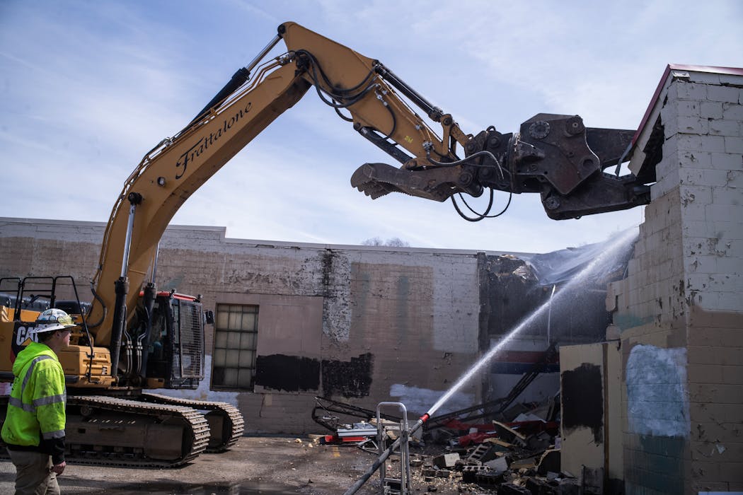 An excavator begins demolition work at the former O'Reilly Auto Parts store that was burned during riots in 2020.