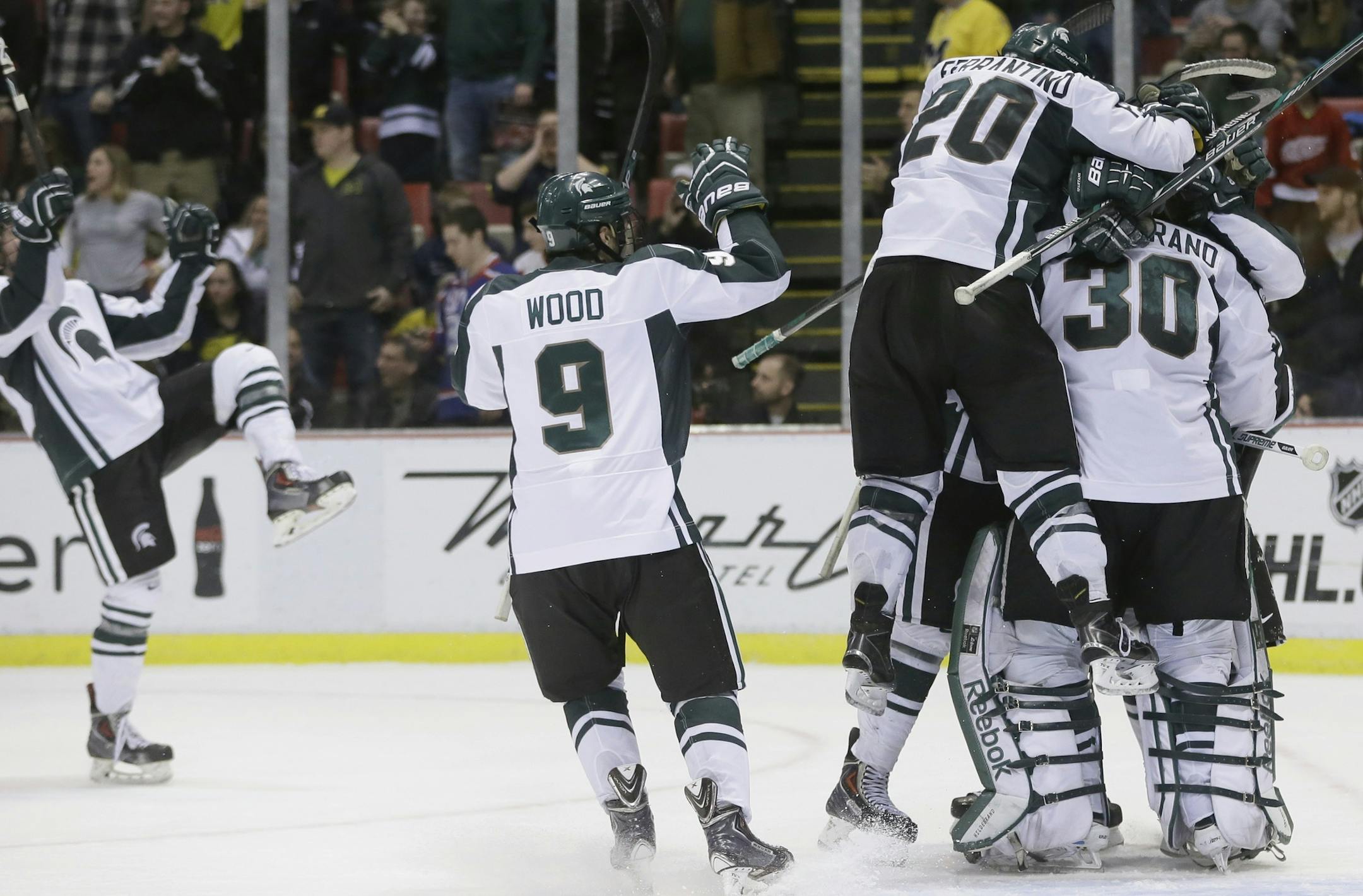 Michigan State hockey players jump on goalie Jake Hildebrand (30) after the third period of an NCAA college hockey game against Michigan, Friday, Jan. 30, 2015 in Detroit. Michigan State defeated Michigan, 2-1. (AP Photo/Carlos Osorio)