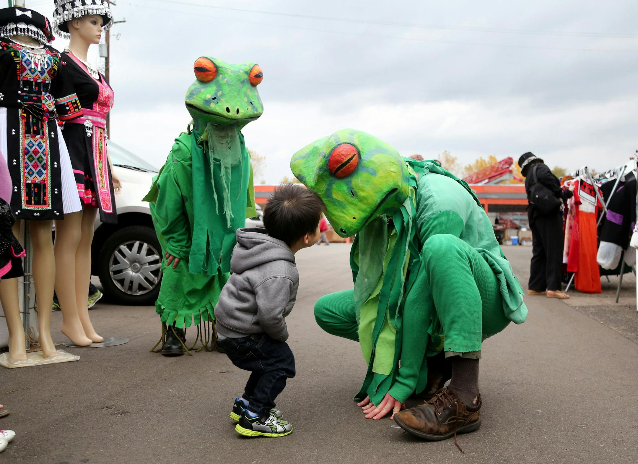 A marimba band concert and pageant of the frogs celebrated the conclusion of FrogLab at the Hmongtown Marketplace mall Saturday, Oct. 15, 2016, in St. Paul, MN. Here, Touger Khang, 2, center, whose family have a nearby booth in the mall, is intrigued with the large frogs from In the Heart of the Beast Puppet and Mask theatre at the event.