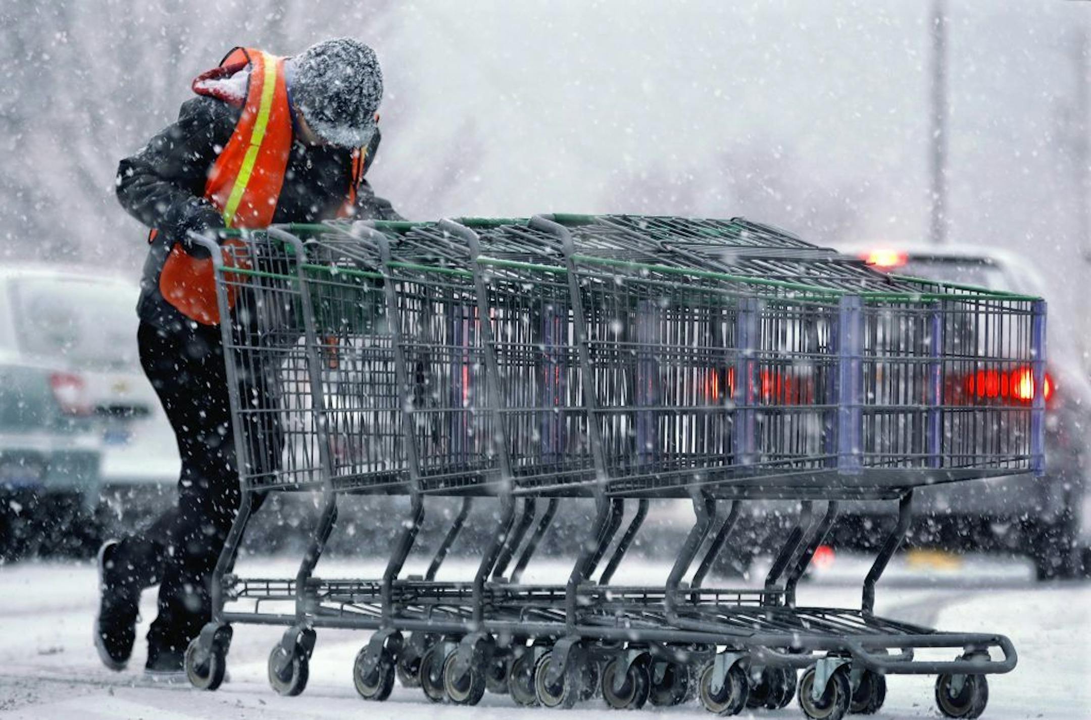 A shopping center employee struggles against strong winds and falling snow as a fast moving winter storm moves into the Midwest Friday, Dec. 13, 2013, in Springfield, Ill. A winter weather advisory extends from Missouri to western New York, according to the National Weather Service. Boston and most of southern New England may see 6 to 12 inches of snow while areas just north and east of the New York may get as much as 10 inches.