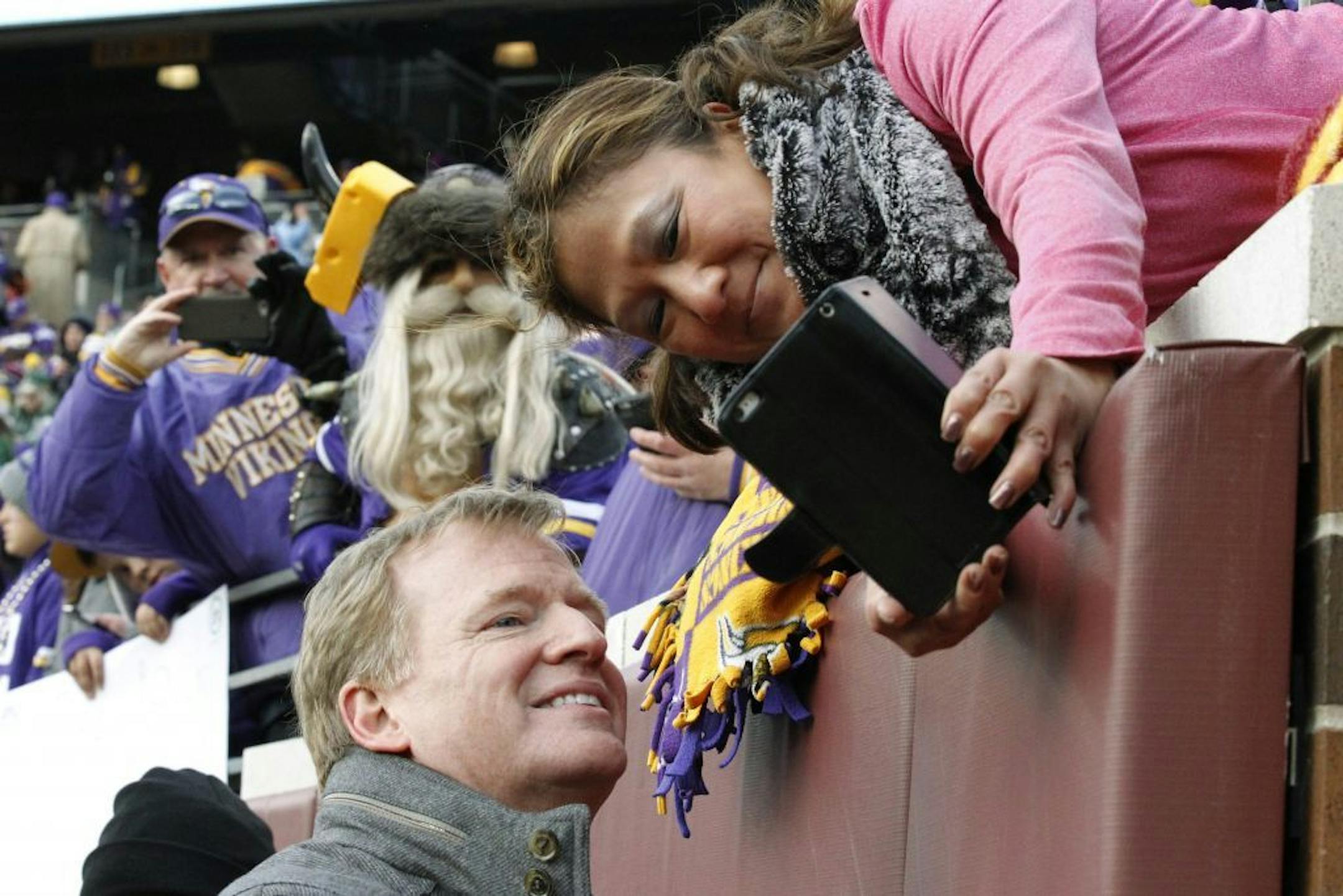 NFL commissioner Roger Goodell poses for a selfie with a fan before an NFL football game between the Minnesota Vikings and the Green Bay Packers in Minneapolis, Sunday, Nov. 22, 2015.