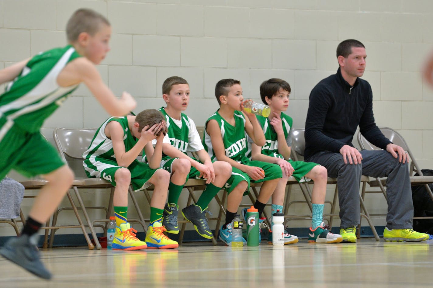 Players on one of Edina's fourth-grade boys' basketball traveling teams watched a tournament game against Chanhassen, catching their breath beside assistant coach Ryan Himley.