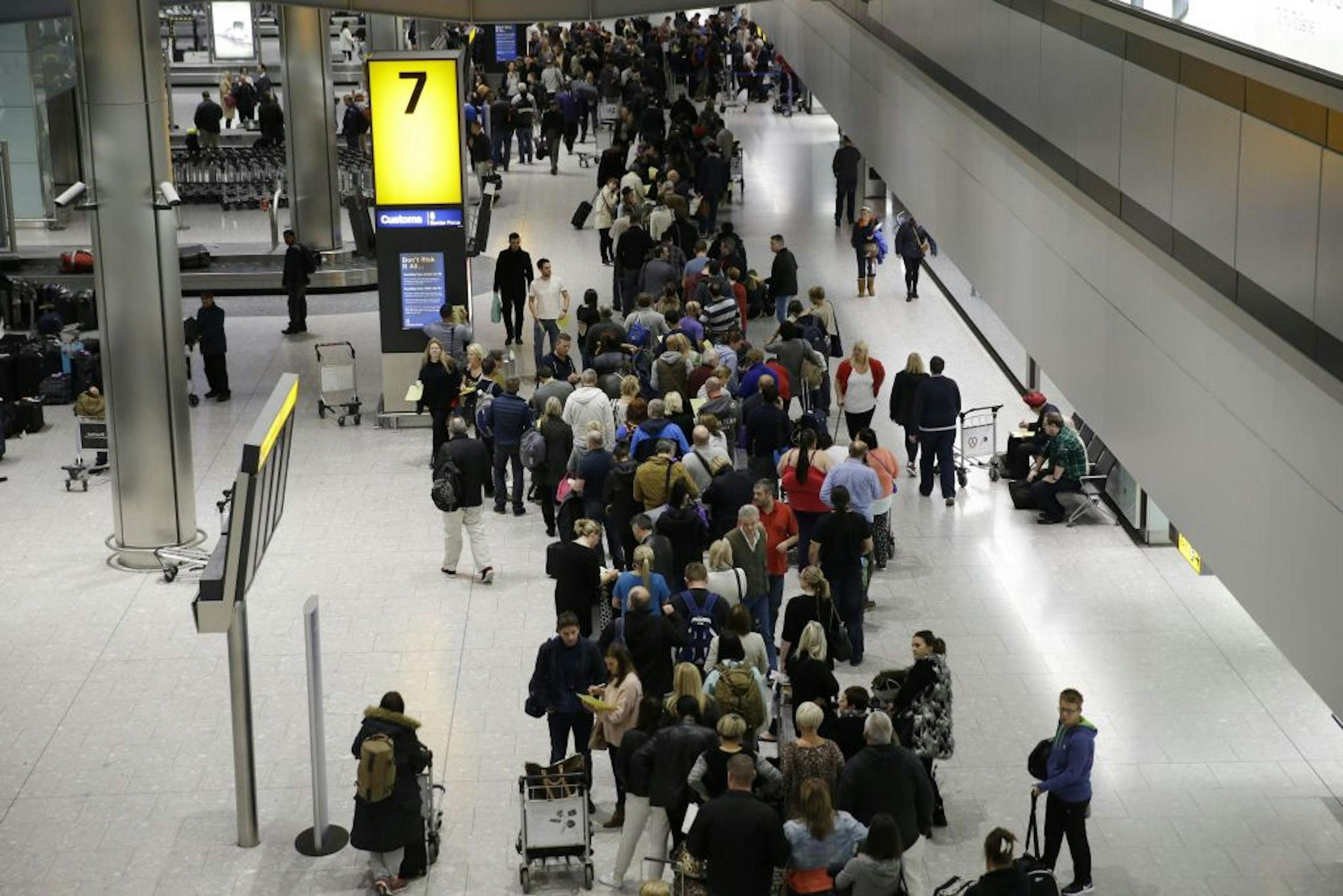 People queue in the luggage hall of Terminal 5 at Heathrow Airport in London, Friday, Dec. 12, 2014. London's airspace was closed today due to what authorities say was a computer failure at one of Britain's two air traffic control centres. Britain's national air traffic body says the computer problem that touched off troubles in the system has been fixed and it is in the process of returning to normal operations.