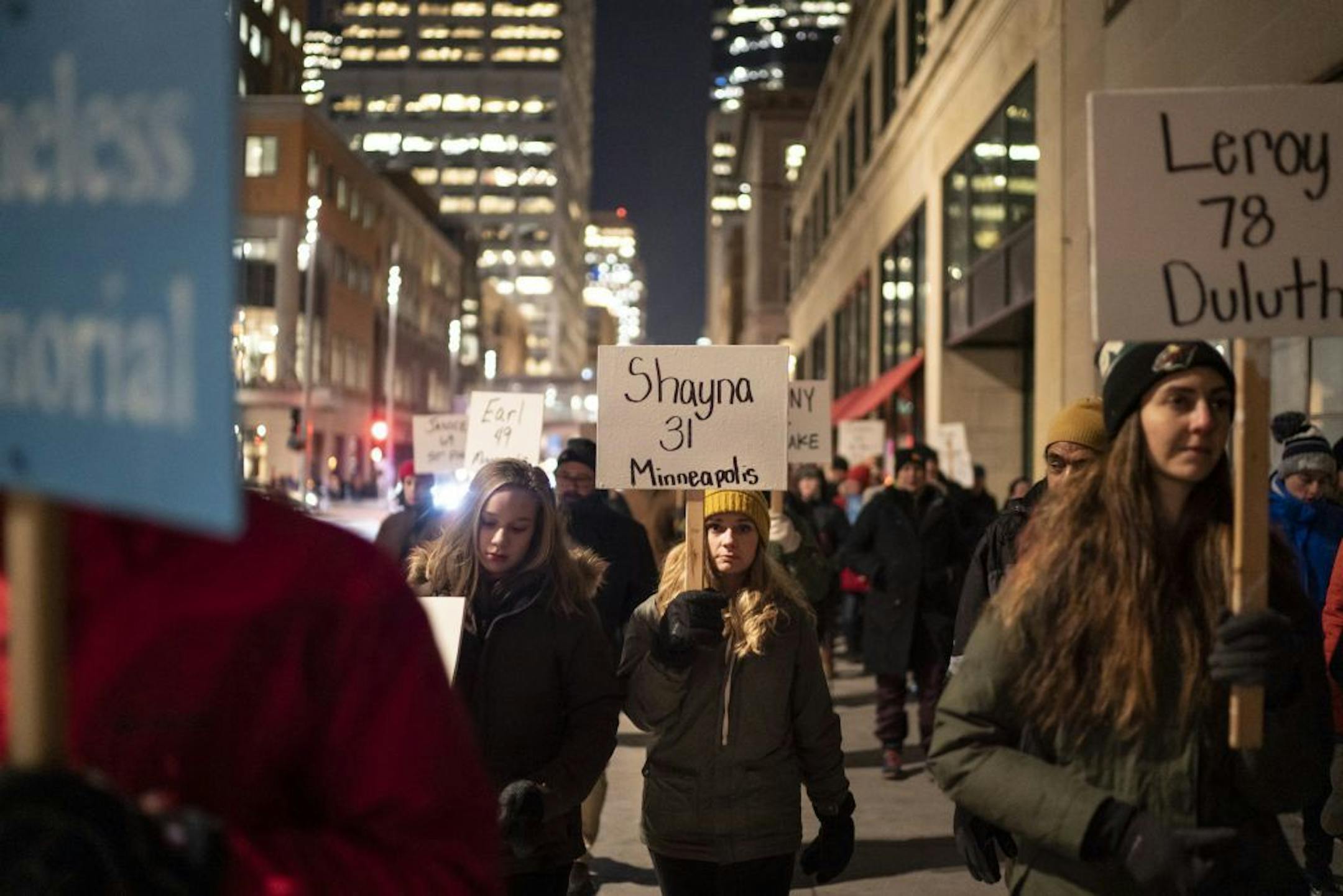 Amy Hedberg, center, of Minneapolis, marched in the silent Homeless Memorial March carrying one of many signs that recognized the 190 homeless, previously homeless and advocates for the homeless that died in 2019 on Thursday, December 19, 2019 through downtown Minneapolis, Minn.