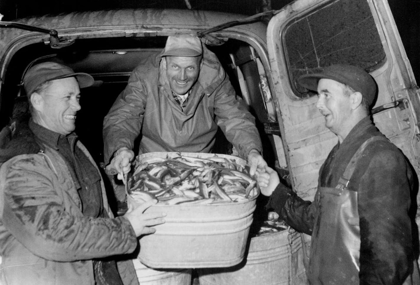 April 23, 1959 Smelt by Tubful - TIn this 1959 photo, three Minneapolis smelt fishermen, Ben Farr, Harold Jorgenson and Pete Strom, left to right, load their panel truck with tubs of smelt caught from the Lester river in Duluth during a particularly heavy run of fish. The group, which also included Duane Farr and John McGuiness, dipped about 450 pounds of smelt in two hours. Jim Peterson, Minneapolis Tribune. ORG XMIT: MIN2016042006425202