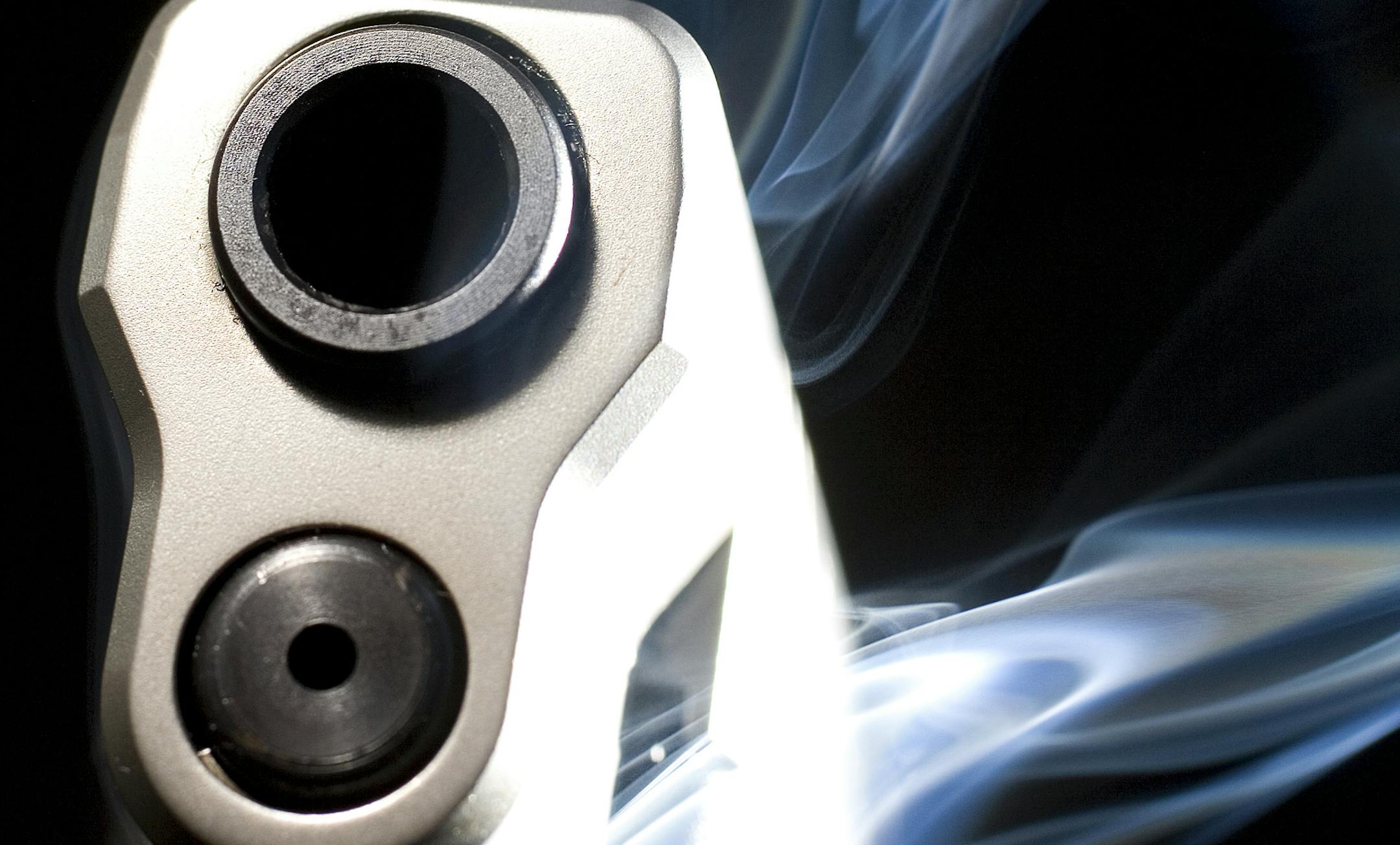 Pistol in the dark with lots of blue smoke rising