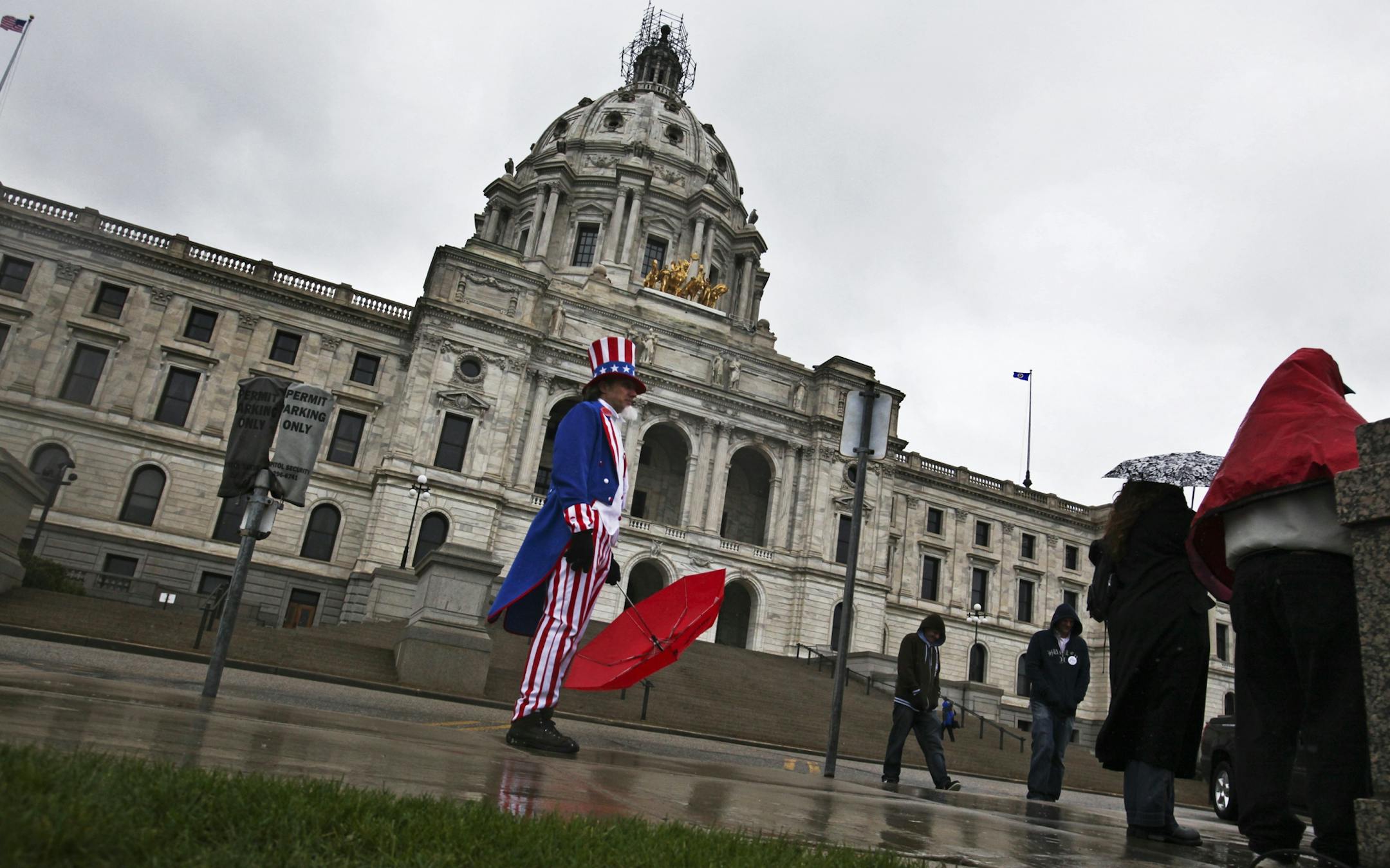 Umbrellas and rain coats were a necessity, even for "Uncle Sam," played by Lee Michaels of Shoreview at the rally outside the Capitol in St. Paul, MN, Saturday, April 28, 2012.