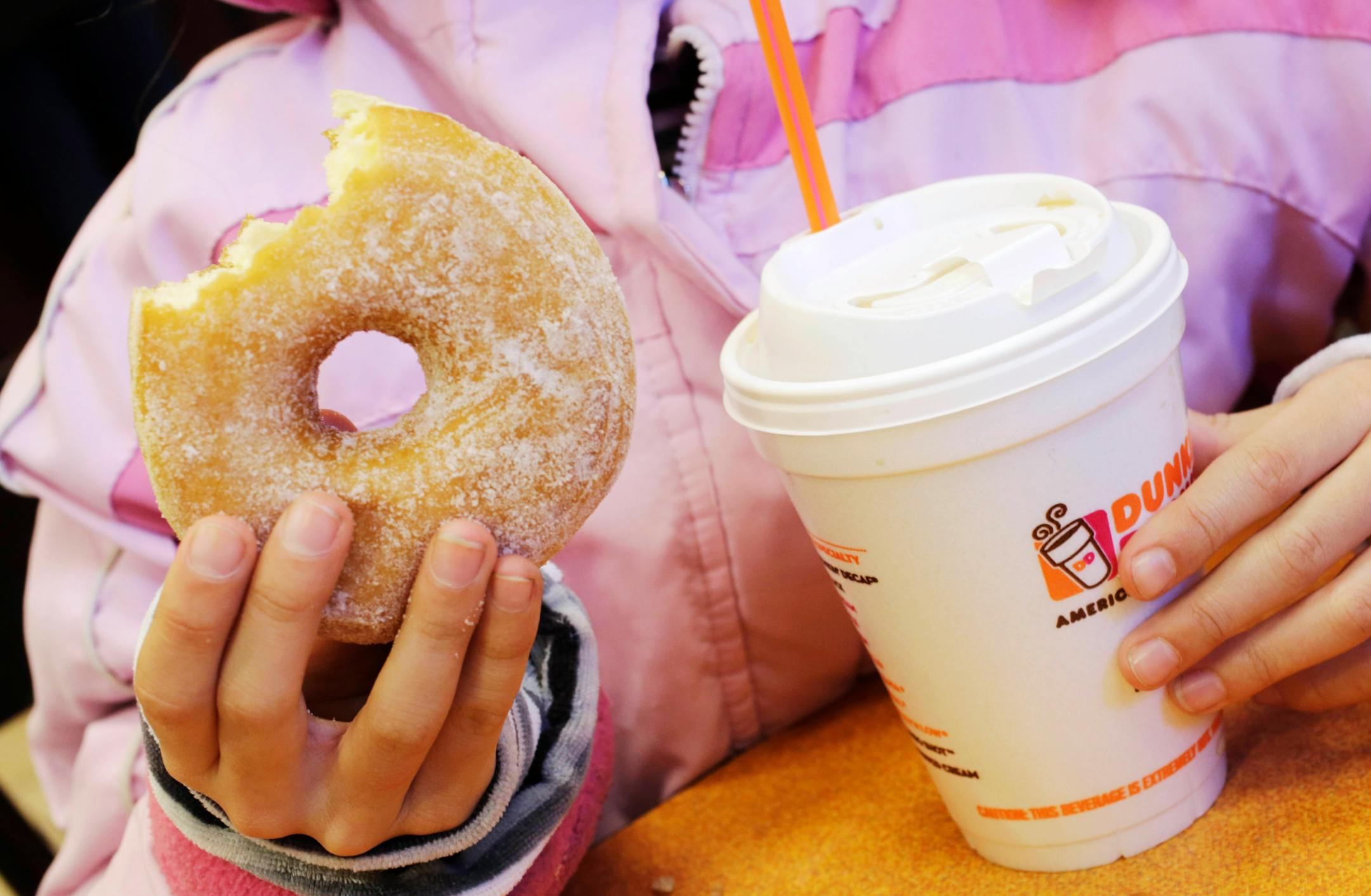 In this 2013 file photo, a girl holds a drink and a doughnut at a Dunkin' Donuts in New York.