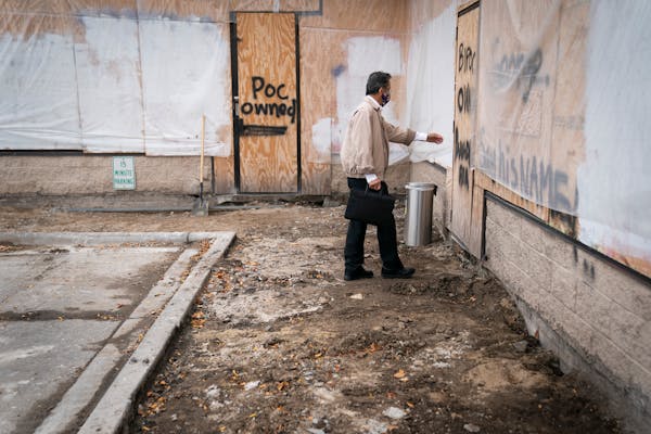 Subway owner Kim Seng tried to see If he could walk through the boarded-up front door of his business as he checked in on the progress of reconstructi