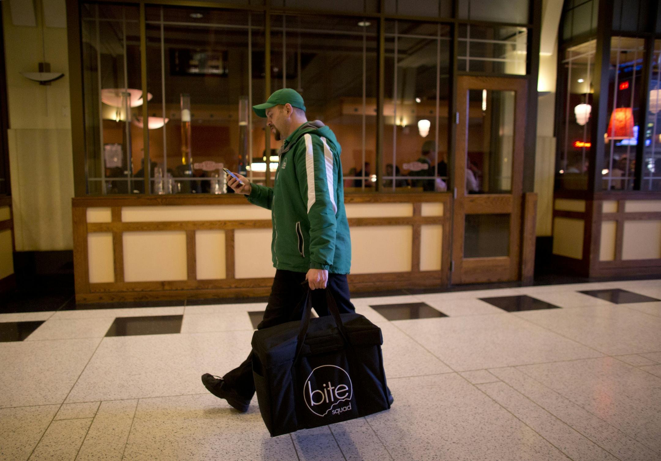 Restaurants are now outsourcing one of their onerous tasks, delivery. With food as a primary focus, restaurants can leave the delivery to a 3rd party. At least six delivery services have sprung up in the Twin Cities in the past year. Sean Dolan, a delivery driver for one of the new ones, Bite Squad, checked his phone while leaving the Rock Bottom Brewery in downtown Minneapolis with a delivery order Thursday evening, April 4, 2013. ] JEFF WHEELER ‚Ä¢ jeff.wheeler@startribune.com