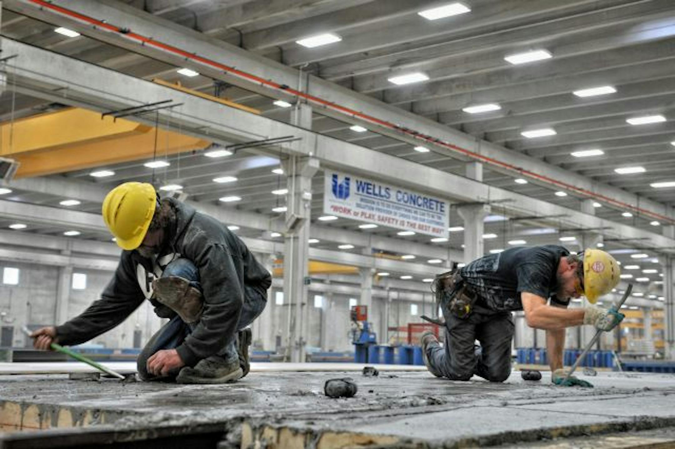 Workers at Wells Concrete in Albany, Minn. clear debris from concrete panels with train tracks that will be used in the new plant to move their product quickly.