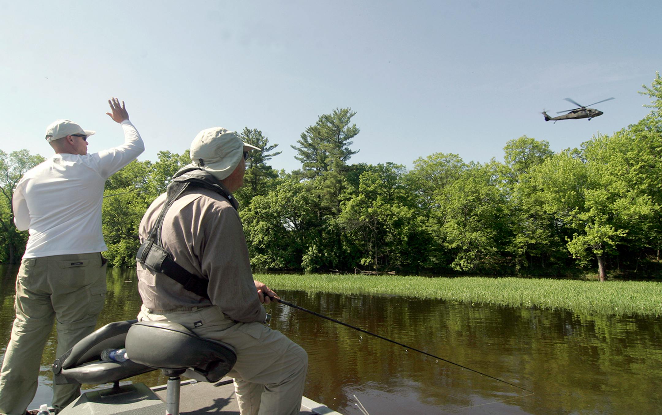 Nate Foster, an Army helicopter pilot, waves to a Blackhawk helicopter that flew over the Mississippi River on Frday and Foster and his grandfather, Swede Anderson, fished.