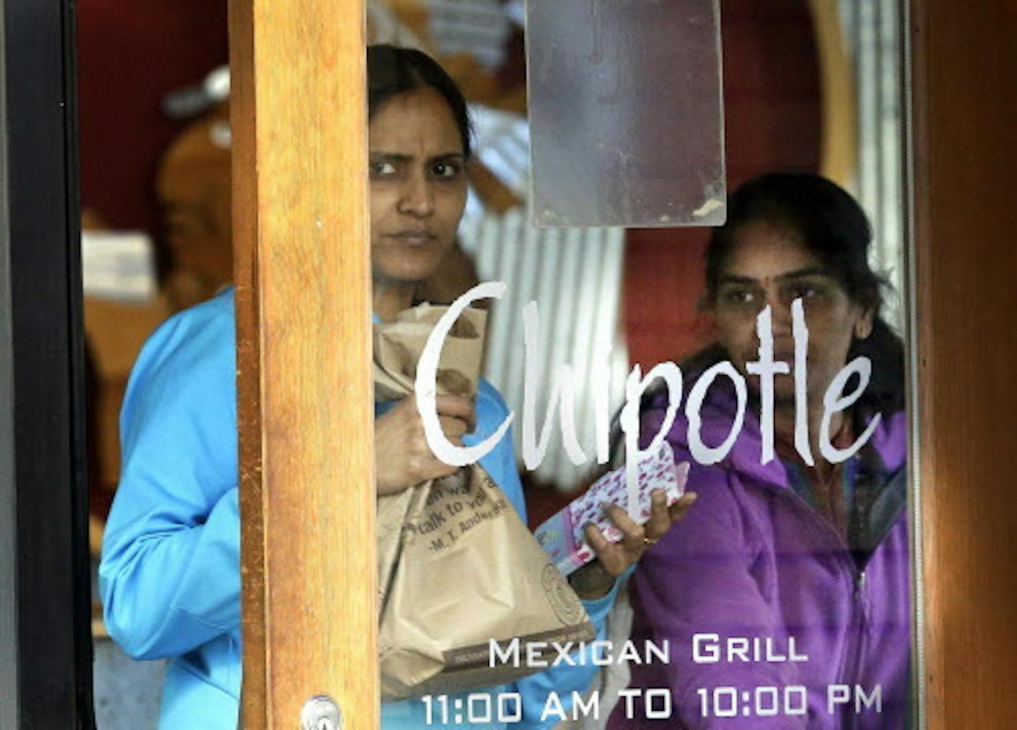 Customers leave a Chipotle restaurant with food in Portland, Ore., on Wednesday, Nov. 11, 2015.