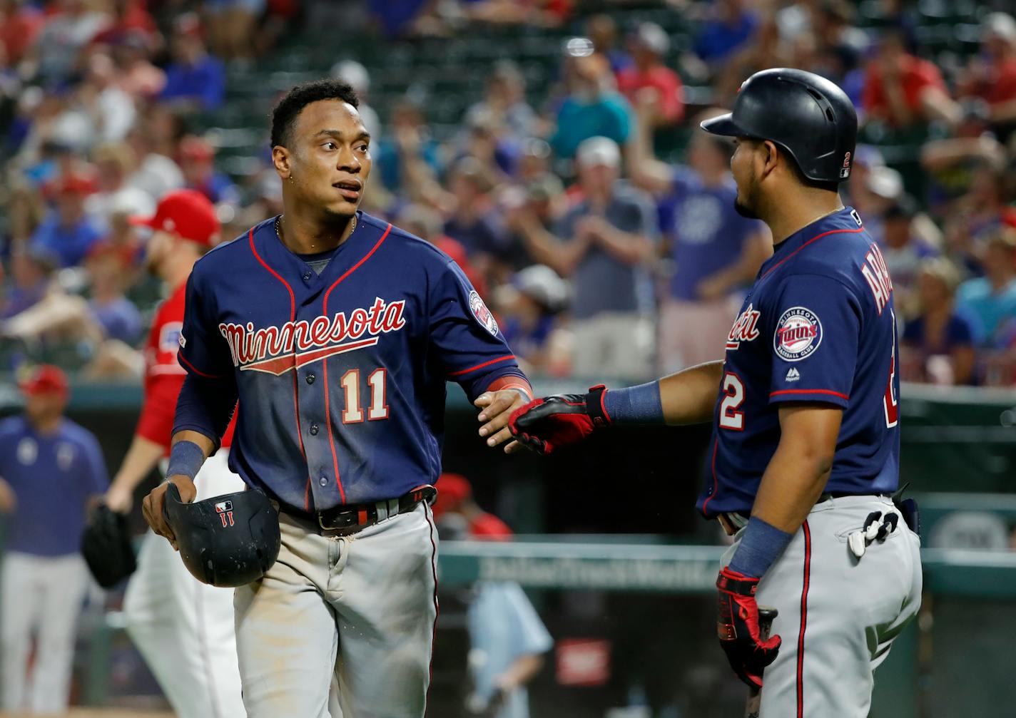 Minnesota Twins' Jorge Polanco (11) and Luis Arraez (2) celebrate after Polanco scored during the eighth inning of the team's baseball game against the Texas Rangers in Arlington, Texas, Saturday, Aug. 17, 2019. (AP Photo/Tony Gutierrez)