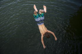 The temperature climbed into the mid-90s on Sunday, but Minnesotans found ways to stay cool. Above: A boy does a backflip off a bridge over Lake of th
