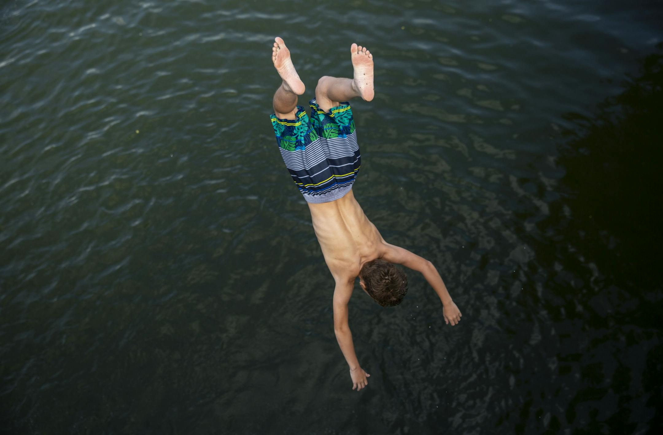 The temperature climbed into the mid-90s on Sunday, but Minnesotans found ways to stay cool. Above: A boy does a backflip off a bridge over Lake of the Isles in Minneapolis on Sunday.
