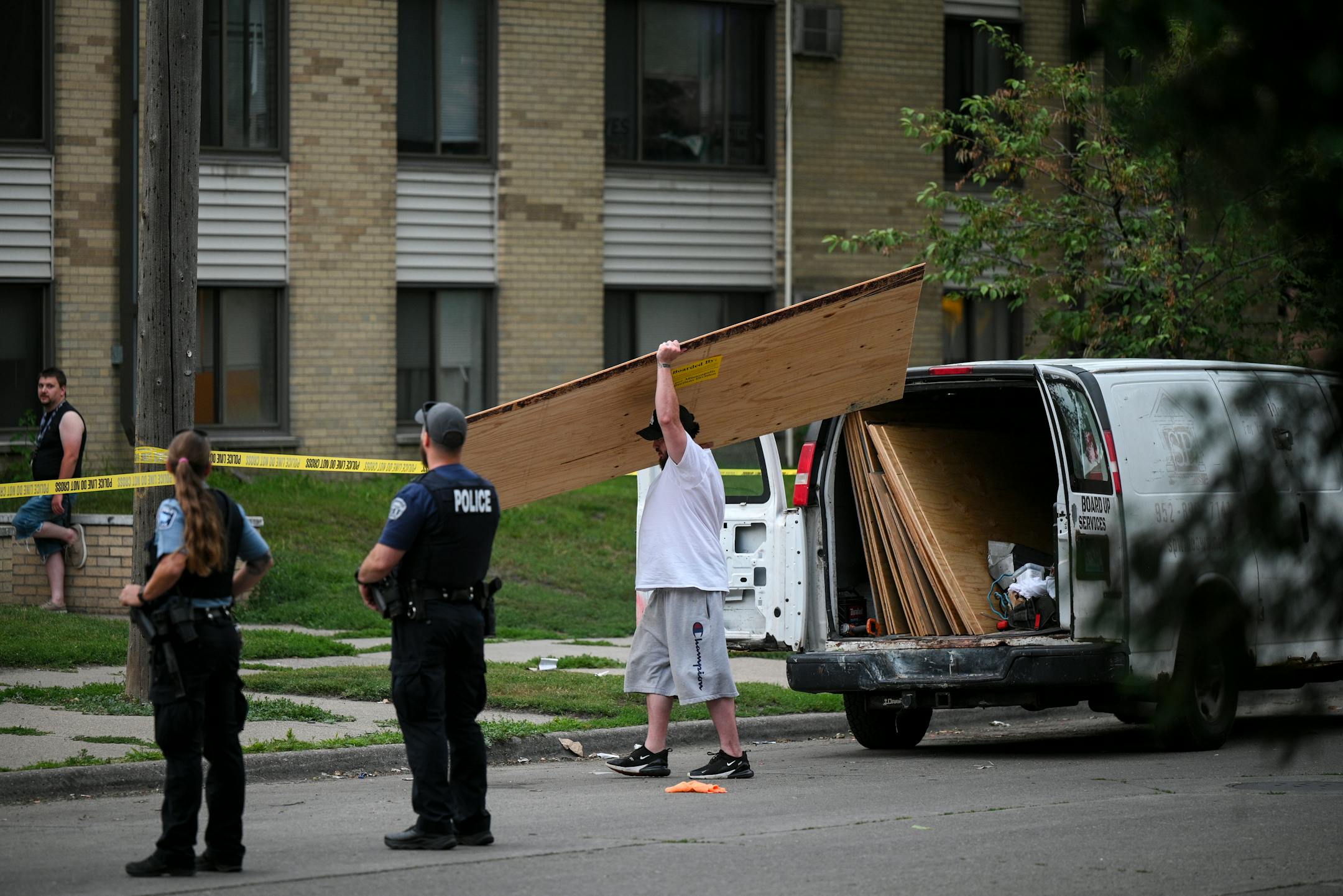 A worker carried a plywood board to cover a broken window before the start of the vigil Thursday.