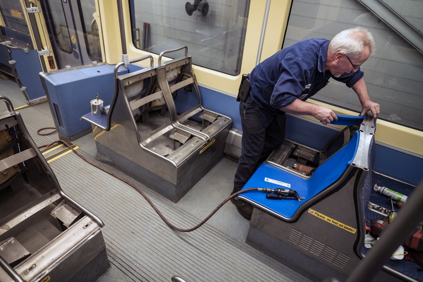 Electromechanical technician Timothy Malmstedt disassembled old cloth seats and installed new plastic seats as part of a test program to try seats that are easier to maintain.