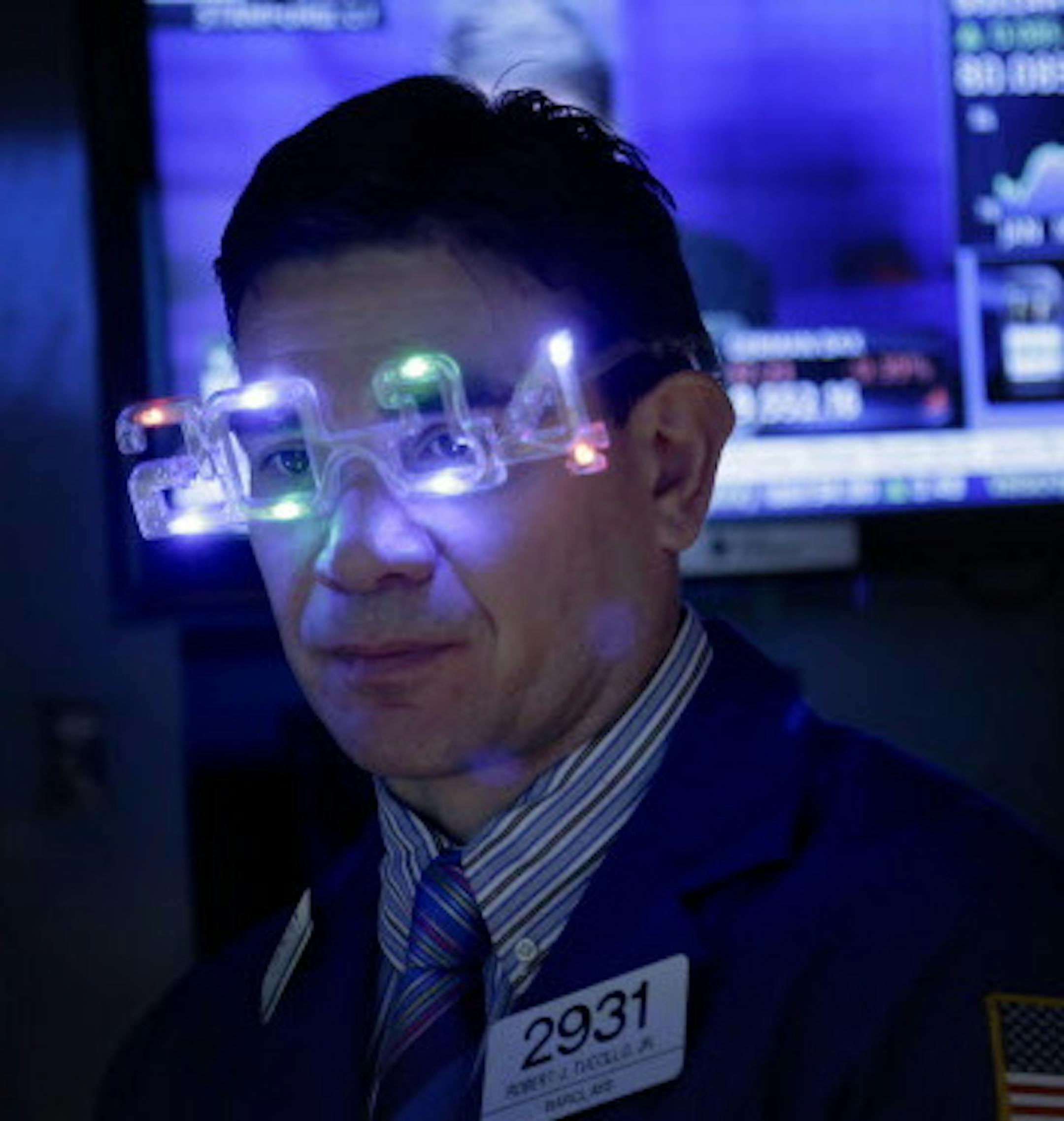 A trader wears glasses celebrating the new year while working on the floor at the New York Stock Exchange in New York, Tuesday, Dec. 31, 2013. (AP Photo/Seth Wenig)