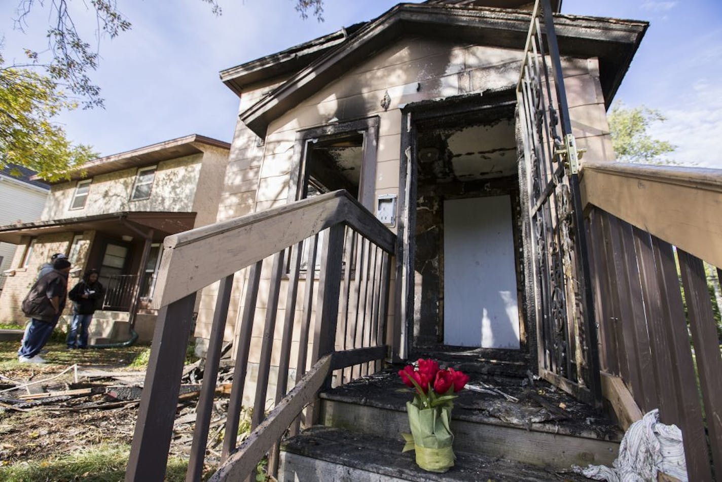 Flowers are seen at site of a house fire on Sunday, October 4, 2015. The fire occurred late in the evening on Saturday, October 3 and there were three victims, all children.