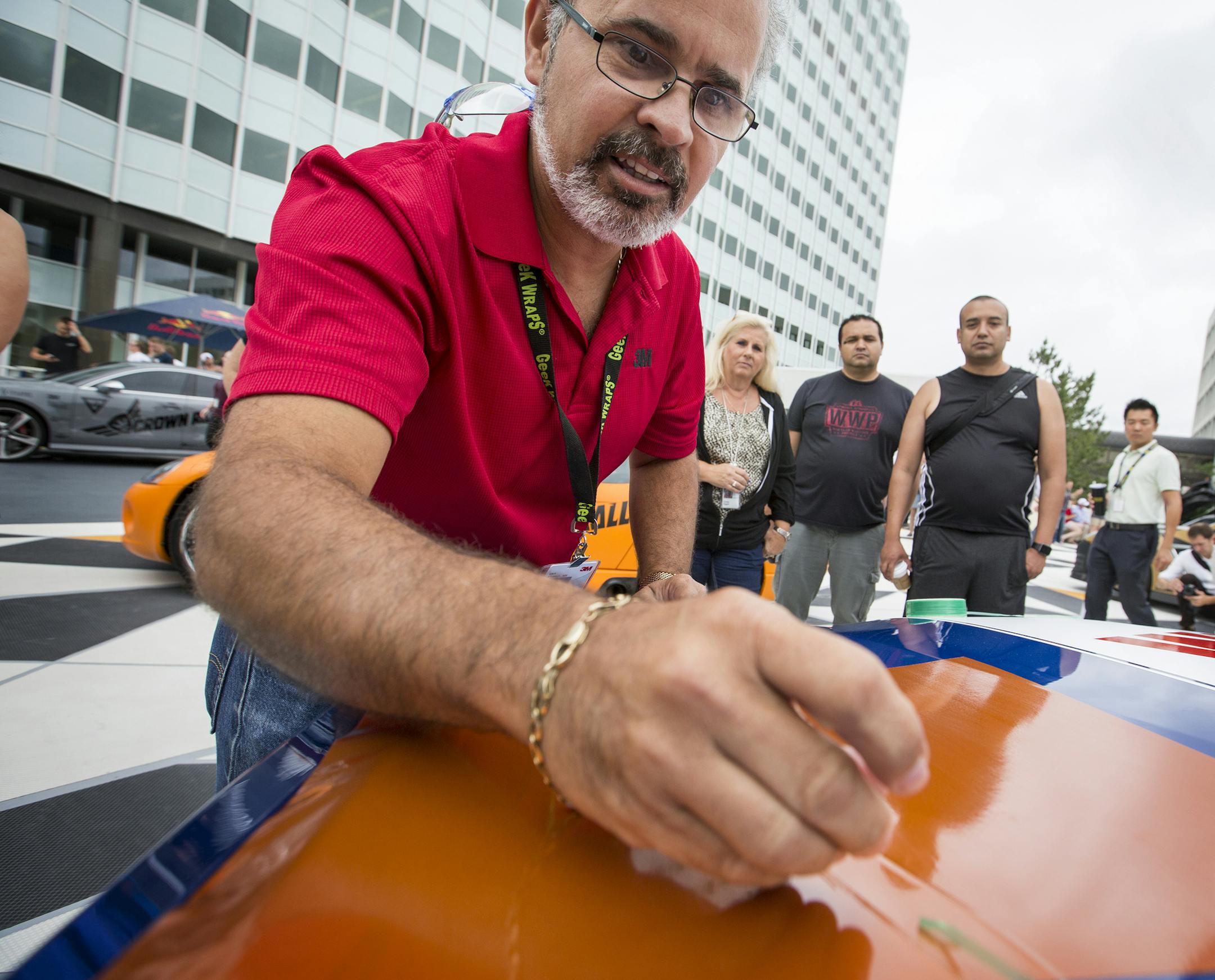 Marcio Oliveira, a technical service supervisor with the 3M graphics installation program, applies a wrap to a car using knife-less tape to make a design. ] (Leila Navidi/Star Tribune) leila.navidi@startribune.com BACKGROUND INFORMATION: The third annual Crown Rally, an automotive event benefitting The Epilepsy Foundation, leaves from the 3M headquarters in Maplewood on it's way to Chicago on Friday, August 12, 2016.