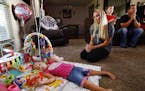 Jayme Magallon watches as her 3-year-old daughter Annalynne play among her birthday balloons as her husband Brandon Magallon, right, and 4-year-old so