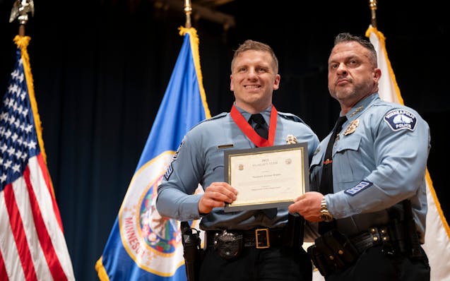 Sergeant Jeremy Depies poses with Minneapolis Police Chief Brian O’Hara after he was awarded a medal of valor for rescuing a drowning four-year-old 