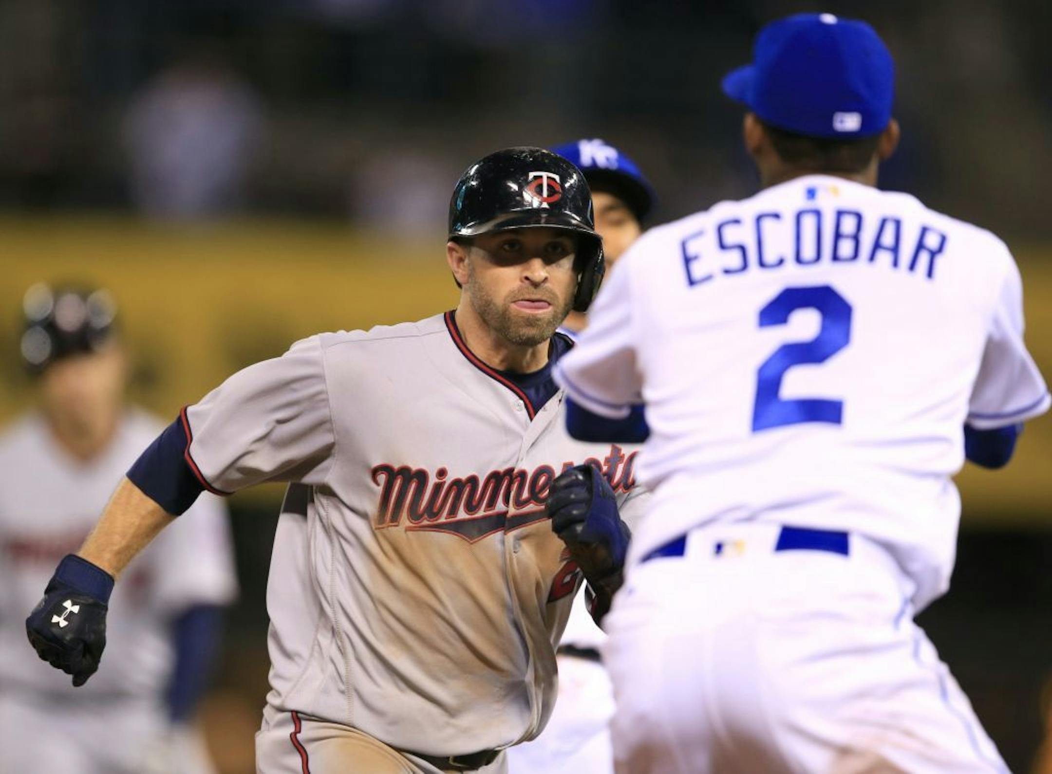 Minnesota Twins' Brian Dozier, left, looks for a way around Kansas City Royals shortstop Alcides Escobar (2) during a rundown in the ninth inning at Kauffman Stadium on Friday, April 8, 2016. Dozier was out on the play. The Royals defeated the Twins 4-3.