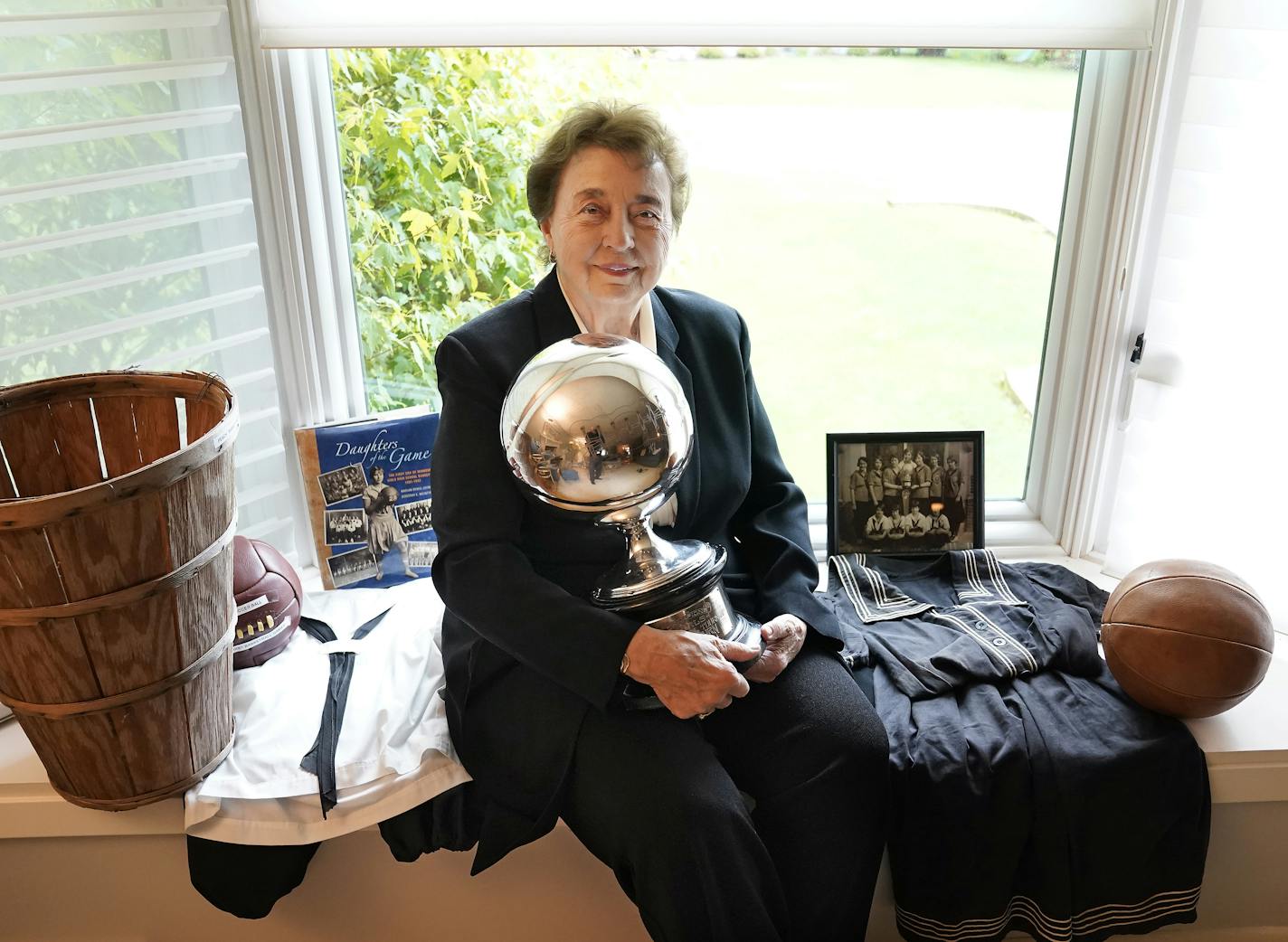 Dorothy McIntyre was a pioneer when she helped run the Minnesota State High School League and posed for a portrait at her home in Edina, Minn. McIntyre was photographed with some prized possessions, including a replica peach basket like the one used by basketball inventor James Naismith in 1892, a book on the history of girls basketball co-authored by McIntyre, uniforms worn by Minnesota girl high school basketball players, who preceded boys to the game, and a replica basketball from the game's early days as well as a trophy and photo from the girls basketball at Sherburne High in 1925. ]