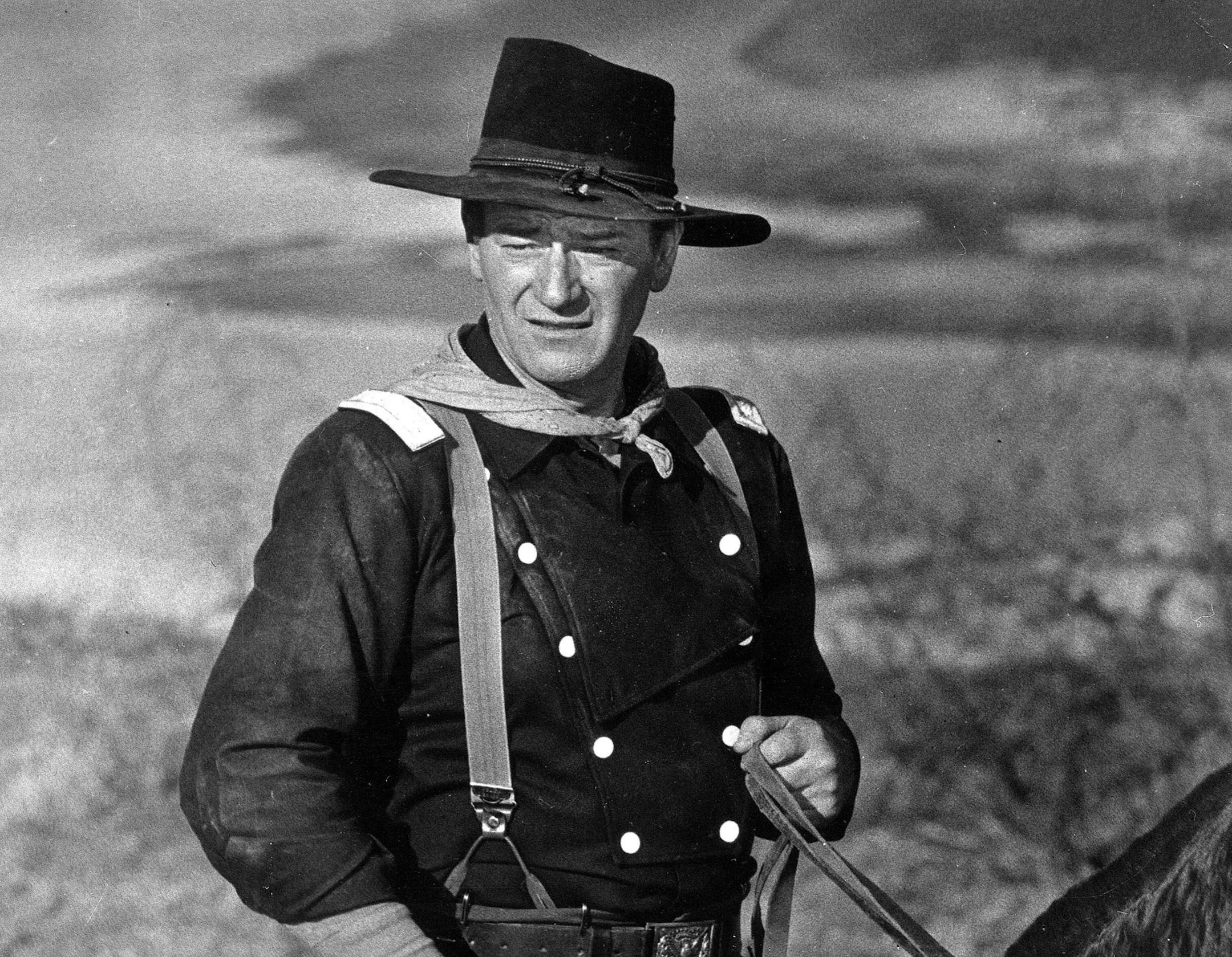 FILE - In this undated photo, John Wayne appears during the filming of "The Horse Soldiers." In the latest move to change place names in light of U.S. racial history, leaders of Orange County‚Äôs Democratic Party are pushing to drop film legend Wayne‚Äôs name, statue and other likenesses from the county‚Äôs airport because of his racist and bigoted comments. (AP Photo, File)