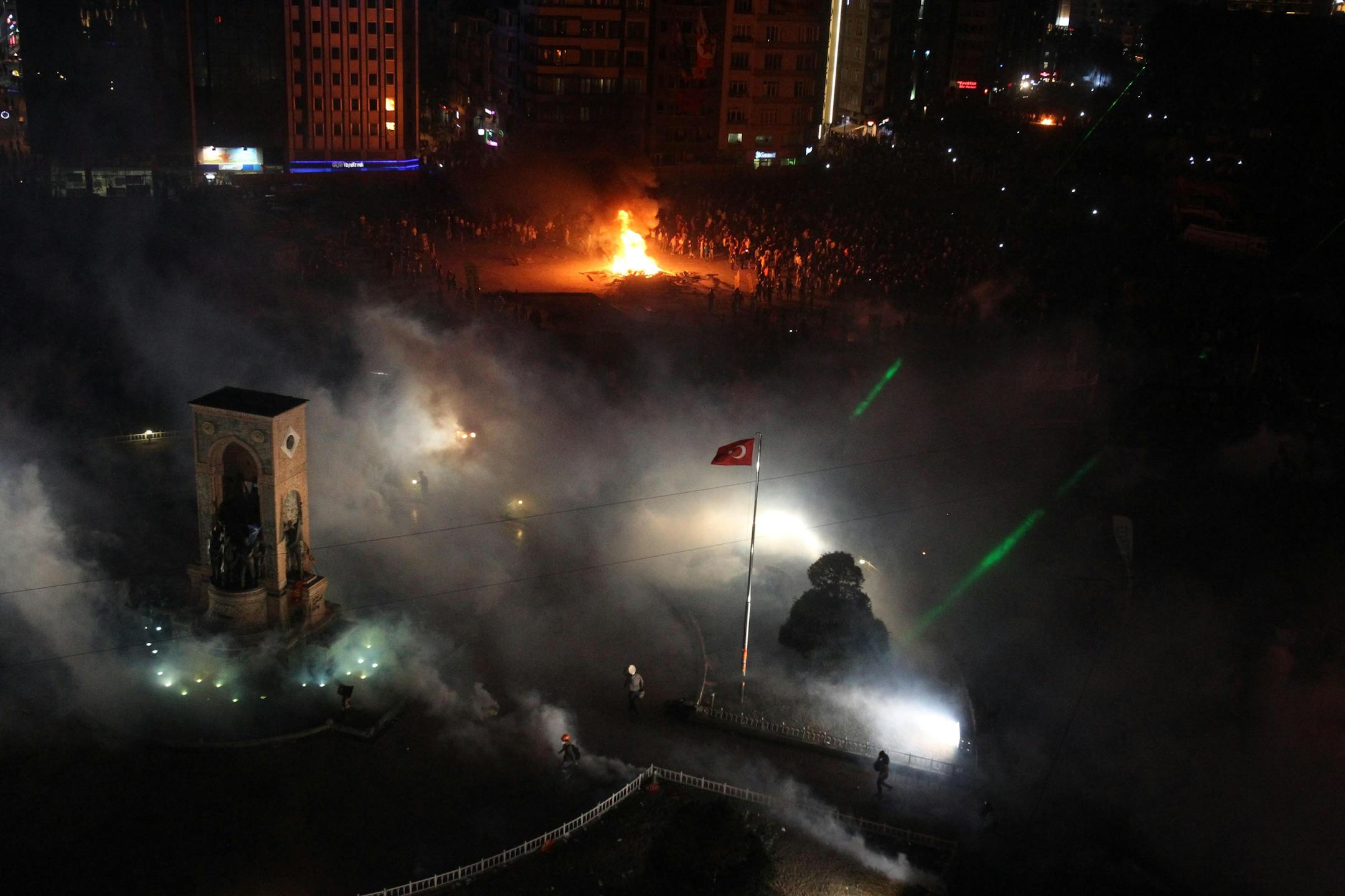 Protesters run to avoid the tear gas as others set fire a barricade during clashes at the Taksim Square in Istanbul on Tuesday, June 11, 2013. Riot police are re-entering Istanbul's Taksim Square after defiant protesters swarmed back in by the thousands.